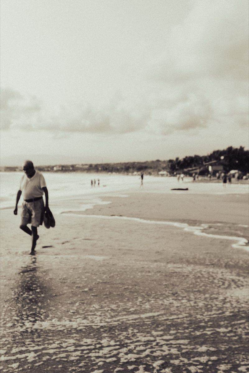Sepia-toned photo of a man walking along the beach